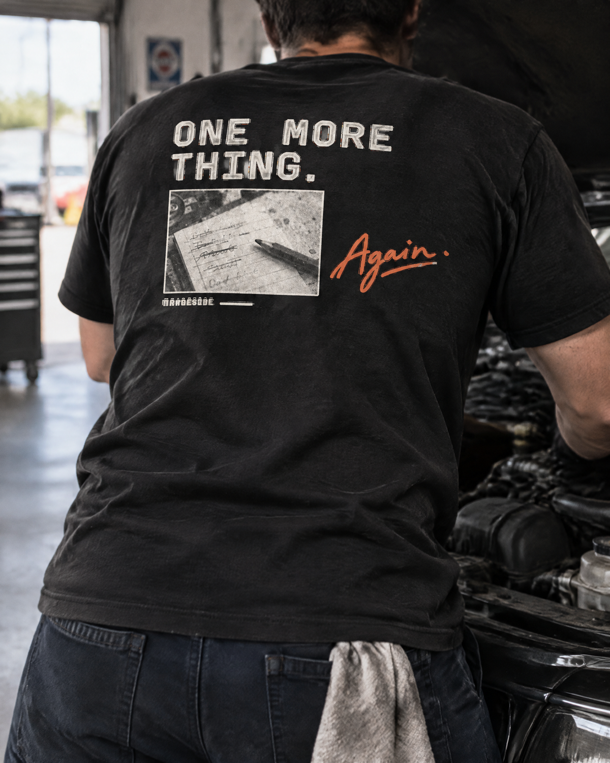 One More Thing tee, back print, worn by a mechanic