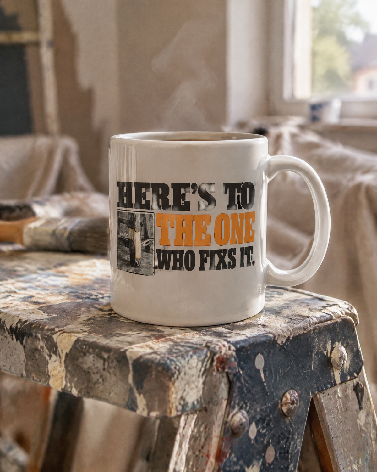 Here's to the One Who Fixed It mug on a paint-spattered stepladder